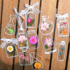 there are many flowers in glass jars on the wooden table with string attached to them