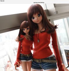 two dolls standing next to each other in front of a window