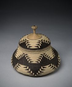 a black and white basket sitting on top of a gray surface with a brown handle