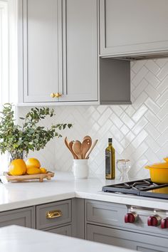 a white kitchen with gray cabinets and yellow dishes on the countertop, next to a cutting board