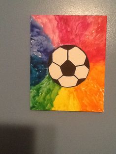 a painting of a soccer ball on a multi - colored background is hanging on the wall