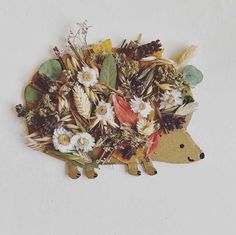 an animal made out of flowers and leaves on top of a piece of white paper