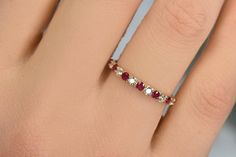 a woman's hand with a diamond and ruby ring on top of her finger