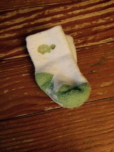 a pair of socks that are on top of a wooden floor and one is green