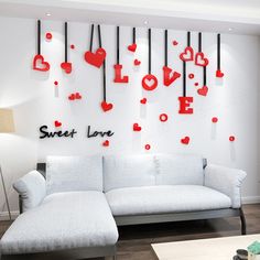 a white couch sitting in front of a wall with red hearts hanging from it's sides