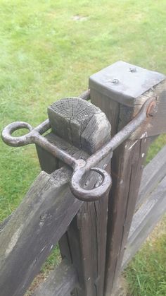 an old wooden gate with a chain and padlock on the top, in front of green grass