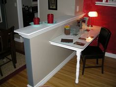 a table with two candles on it in front of a red wall and wooden floor