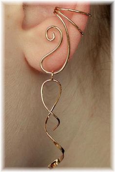 a pair of ear piercings with spiral designs on the back of their ears, in gold