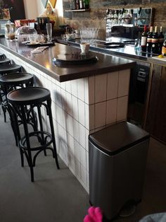 a bar with stools and bottles on the counter