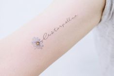 a woman's arm with the word love written on it and a daisy tattoo