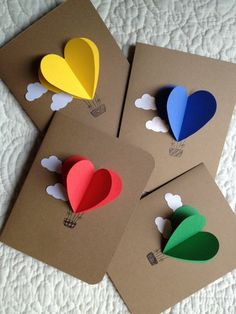 three cards with hearts cut out of them on top of a sheet of brown paper