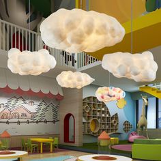 the interior of a children's playroom with colorful furniture and clouds hanging from the ceiling