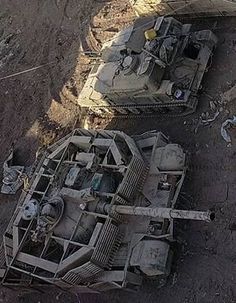 two old tanks sitting on top of a dirt field