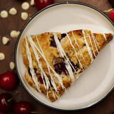 a piece of cherry scones with icing on a plate next to cherries