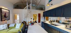 a living room filled with furniture and a spiral stair case in front of a kitchen