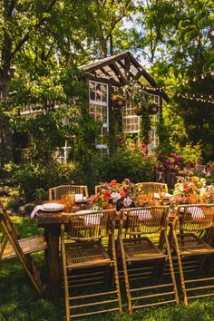 an outdoor dining table set up in the grass with chairs around it and flowers on the table