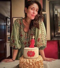 a woman sitting in front of a cake with a figurine on the top