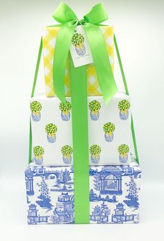 three wrapped gift boxes with green ribbons and bows on them, stacked in front of each other