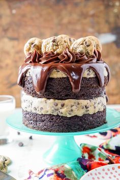 a cake with chocolate frosting and cookies on top is sitting on a plate next to a glass of milk