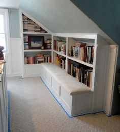 an attic bedroom with bookshelves and built - in benches