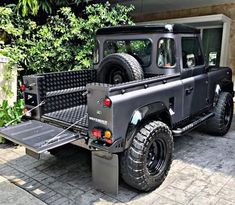 a black truck parked in front of a building next to a tree and shrubbery