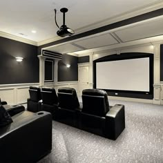 a home theater with black leather chairs and a projector screen