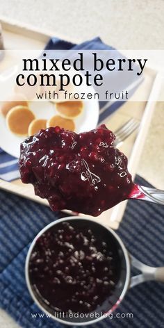 a spoon full of mixed berry compote with frozen fruit next to some pancakes