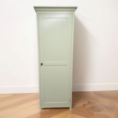 a tall green cabinet sitting on top of a hard wood floor