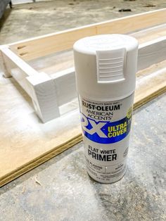 a can of white paint sitting on top of a wooden floor next to plywood