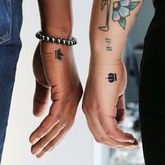 two people holding hands with tattoos on them