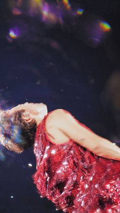 a woman in a red dress floating on top of water with her head above the water