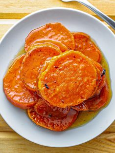 a white plate topped with sliced oranges on top of a wooden table next to a fork