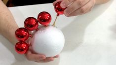 a person holding a white ball with red ornaments on it