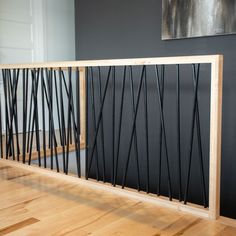 a wooden railing with metal bars on it in a room that has hardwood floors and gray walls