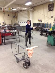 a woman in a garage pulling a cart with something on it