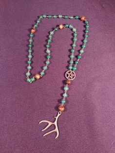 a long beaded necklace with an antler charm on it's end and beads around the neck