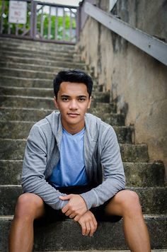 a young man is sitting on some stairs