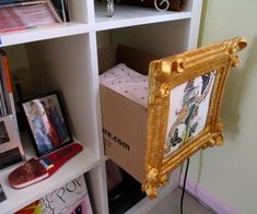 there is a gold framed picture in the corner of this bookshelf with pictures on it