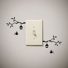 a light switch sitting on top of a wall next to a tree branch with birds