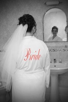 the bride is getting ready to go into her wedding dress in the bathroom with her mother