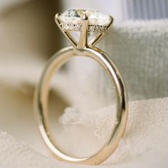 a close up view of a diamond ring on a white cloth with the background visible