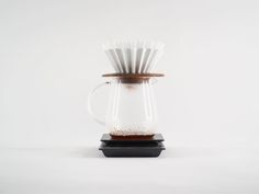 a glass coffee pot filled with liquid and paper straws on top of a black coaster