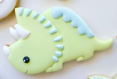 a cookie decorated like a dinosaur laying next to cookies