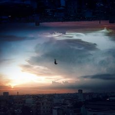 a person is flying through the air in front of a cityscape at sunset