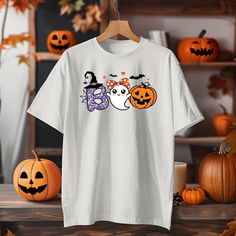 🎃 Get Ready for Spooky Cuteness with Our Adorable Boo Halloween Shirt! 🎃 This Boo Halloween t-shirt is perfect for adding some cuteness to the spooky season! Featuring an adorable ghost with a bow, a smiling pumpkin, and a witchy "B," this tee is the perfect blend of spooky and sweet. Whether you're getting ready for trick-or-treating or just want to show off your love for Halloween, this shirt is a must-have. 👻 Why You'll Love It: Soft and comfy fabric for easy wear throughout the day. Super cute Halloween design with a ghost, pumpkin, and witchy vibes. Available in multiple sizes for both women and kids. A great Halloween gift for someone who loves cute and spooky fashion. 🕸️ Product Details: Material: High-quality cotton blend for a comfortable, breathable fit. Fit: Relaxed unisex s White Halloween Shirt With Character Print, Fun White Halloween T-shirt, Fun White T-shirt For Halloween, Halloween White Graphic Tee, Halloween Graphic Tee In White, White Halloween Shirt With Letter Print, Fun White Halloween Top, Fun White Top For Halloween, Fun White Tops For Halloween