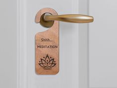 a wooden door handle with the words shh meditation on it and a lotus symbol