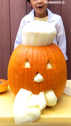 a young boy sitting in front of a carved pumpkin with marshmallows on it