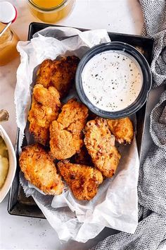 fried chicken sticks with ranch dressing on a tray next to dipping sauce and potato wedges