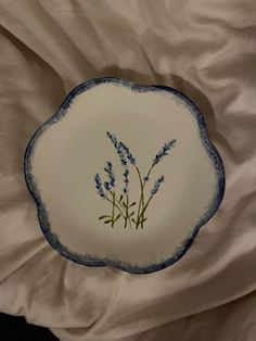 a blue and white plate with lavender flowers on it sitting on top of a bed