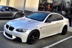 a white bmw car parked in front of a building with two other cars behind it